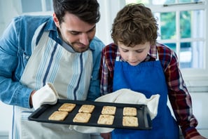 Father holding biscuits tray in the kitchen
